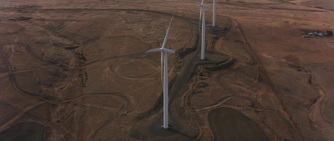 Windmills rotate in a large dirt field
