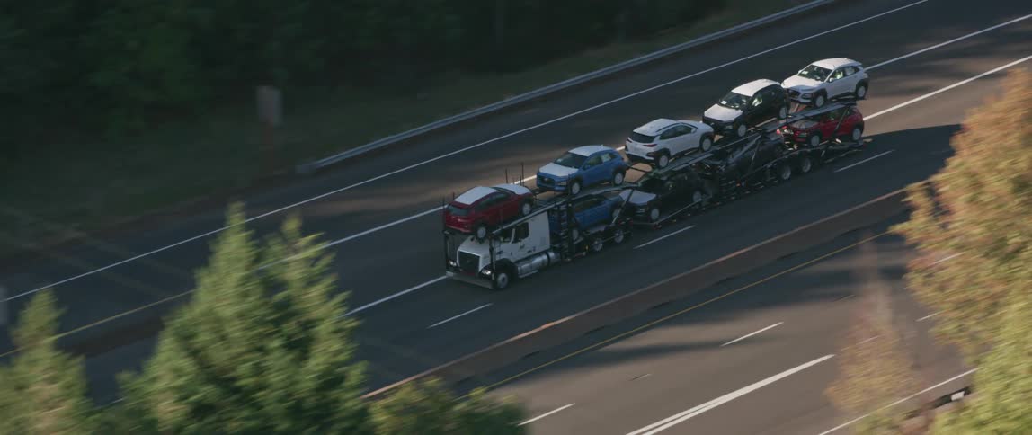 A semi-truck hauls cars on a freeway