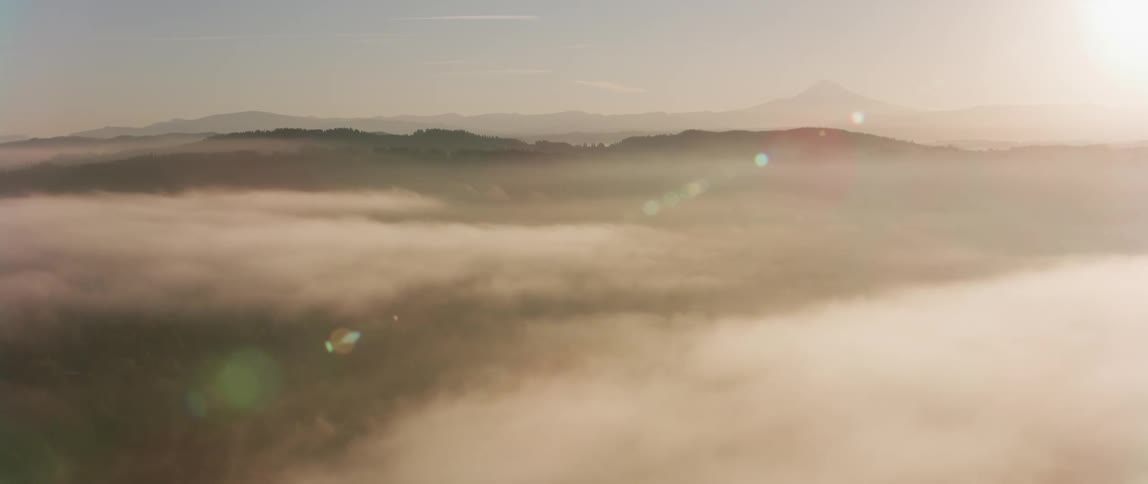The sun shines above white clouds