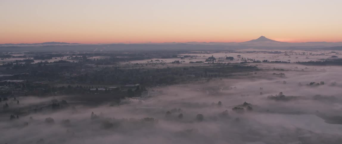 Mist floats over a valley at sunset