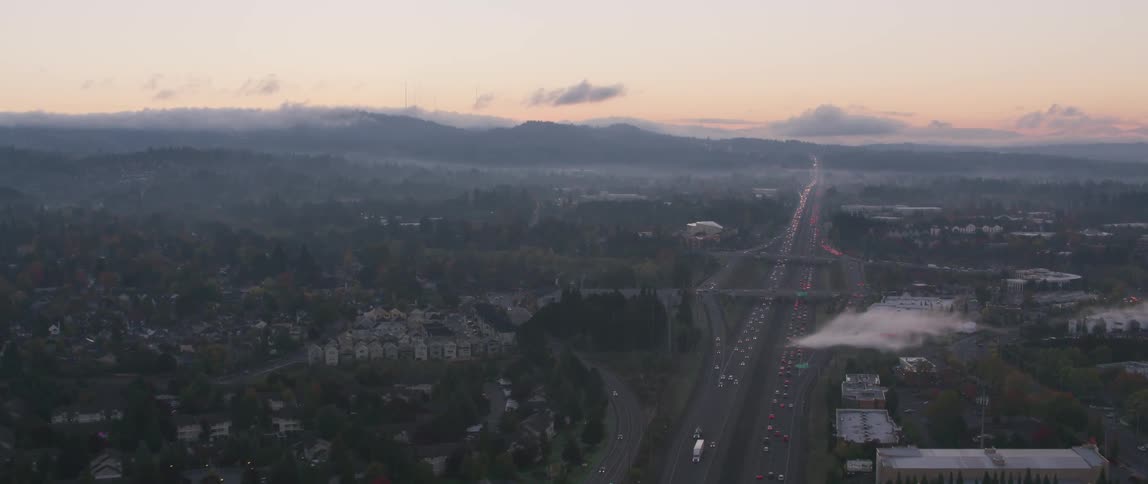 Traffic is flowing on a freeway at dusk