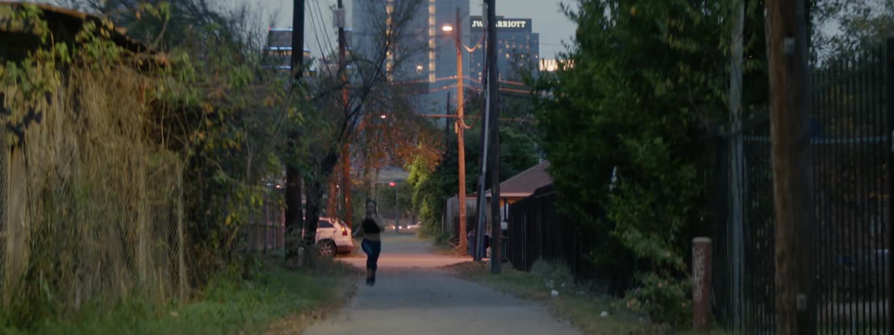 A woman runs down an alleyway