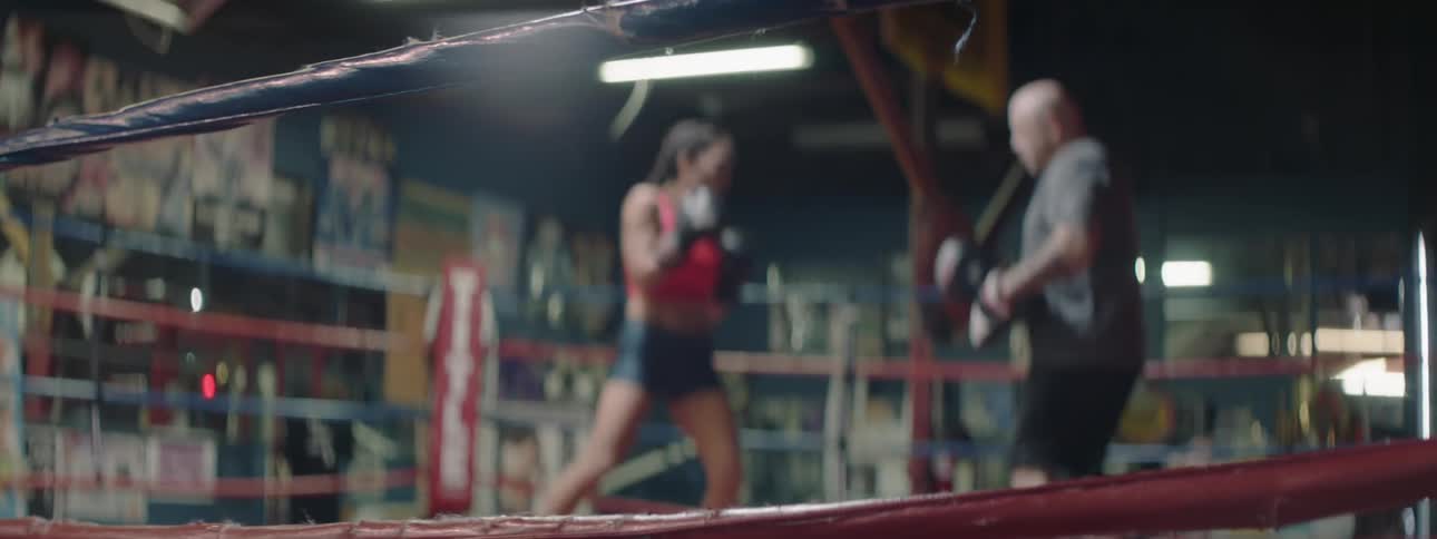 A boxer trains in the ring with a coach