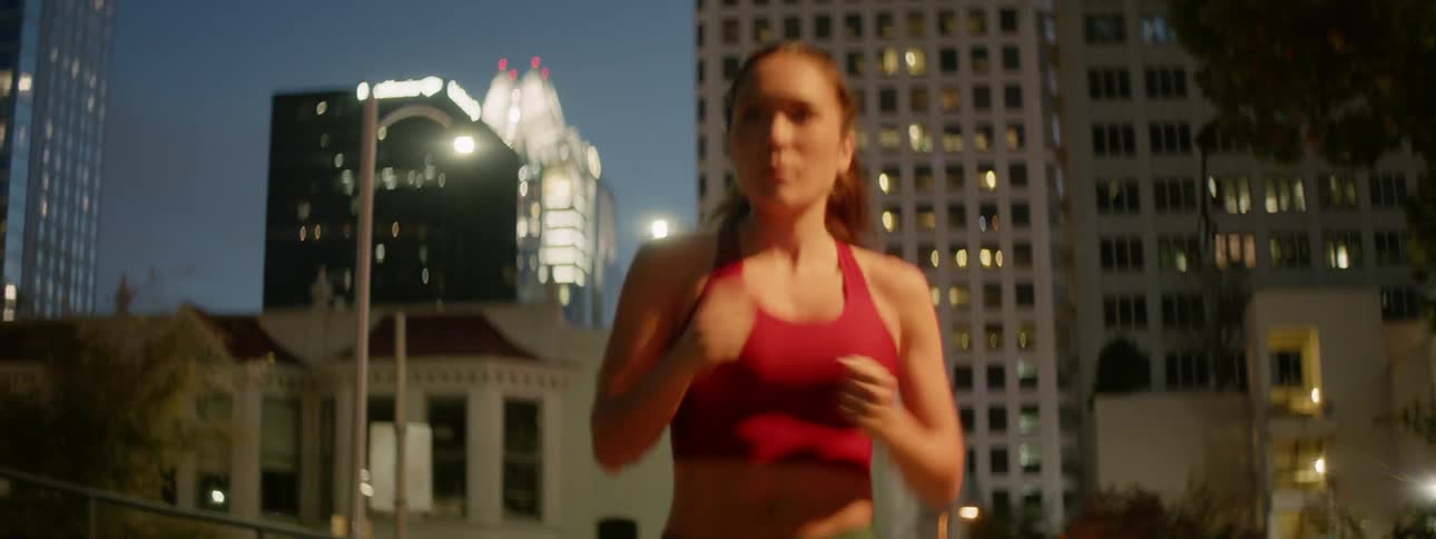 A woman is jogging in a city at night