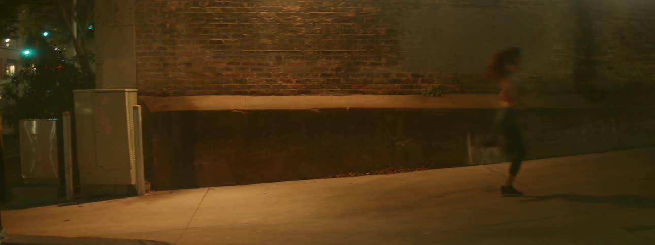 A woman jogs uphill on the sidewalk
