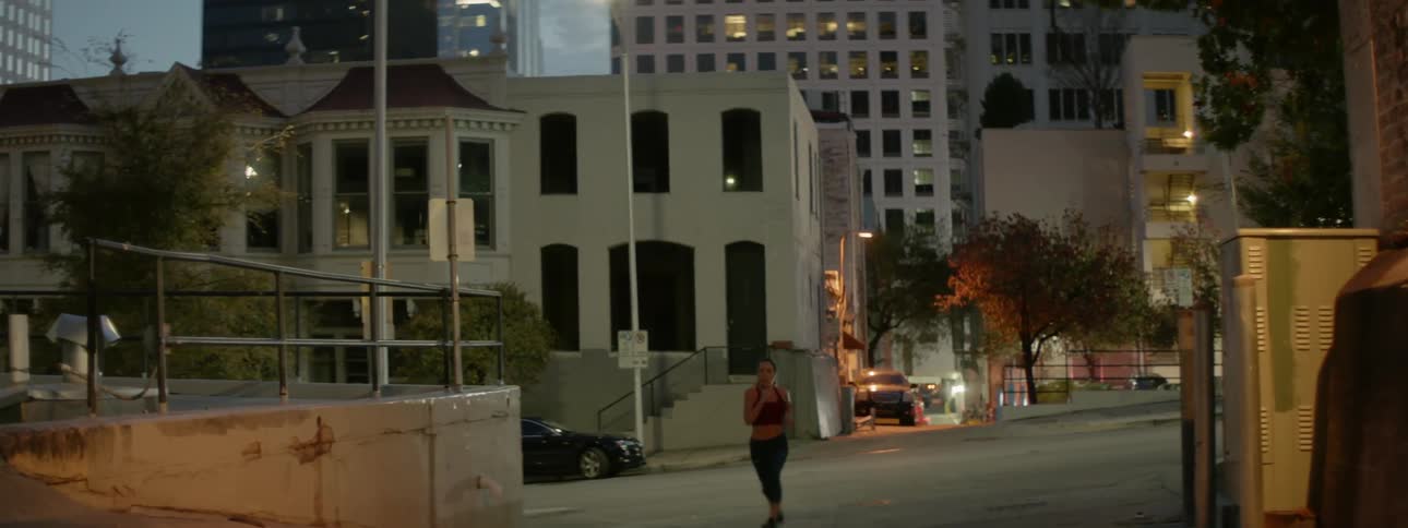 Woman jogging on a city street at dusk