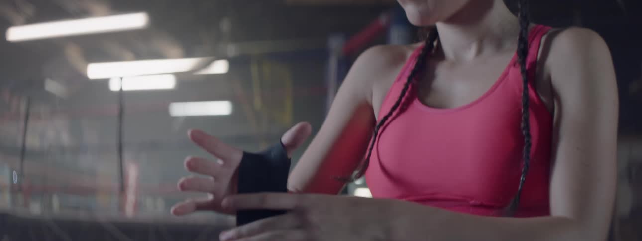 A woman wraps her wrist in a gym