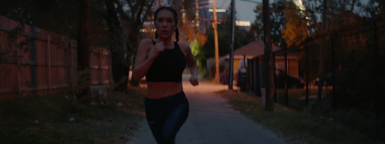 A woman runs on a city sidewalk at night