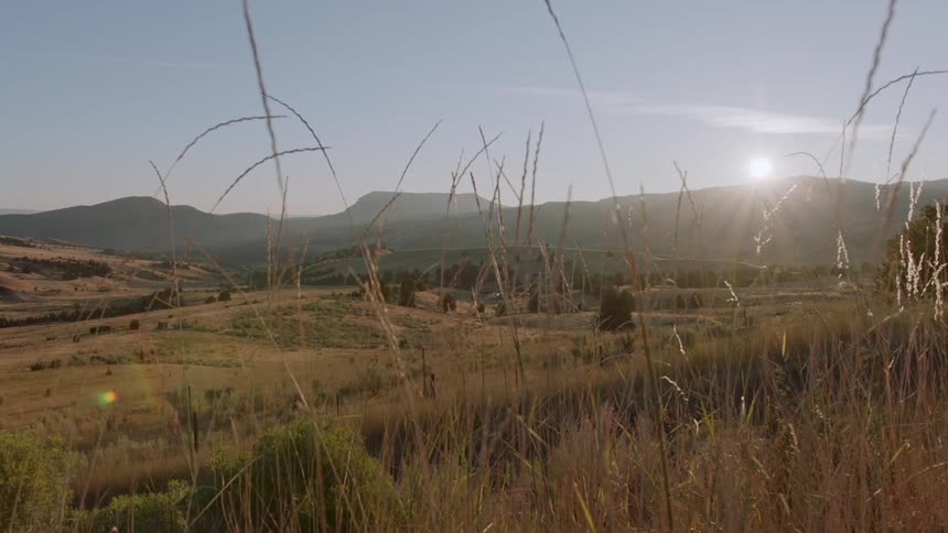 The sun is rising over a valley on a sunny day