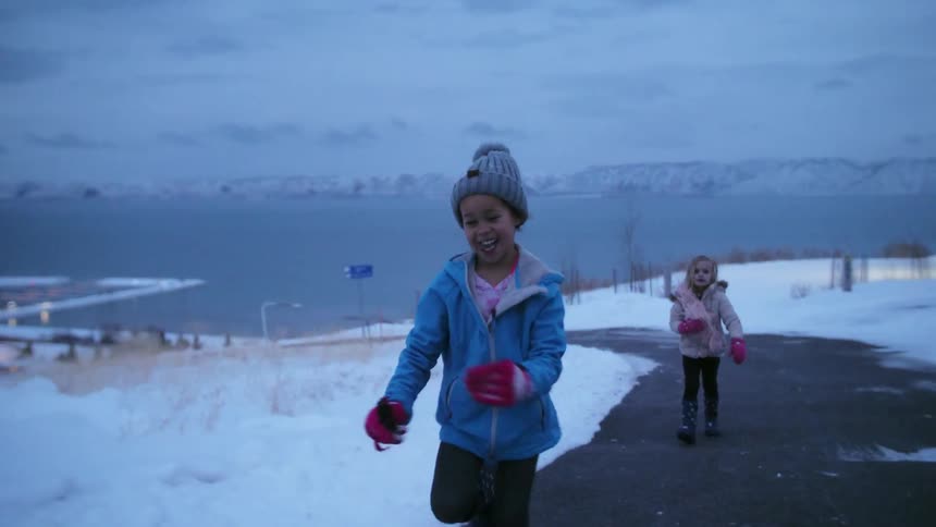 Two young girls laugh and play in the snow