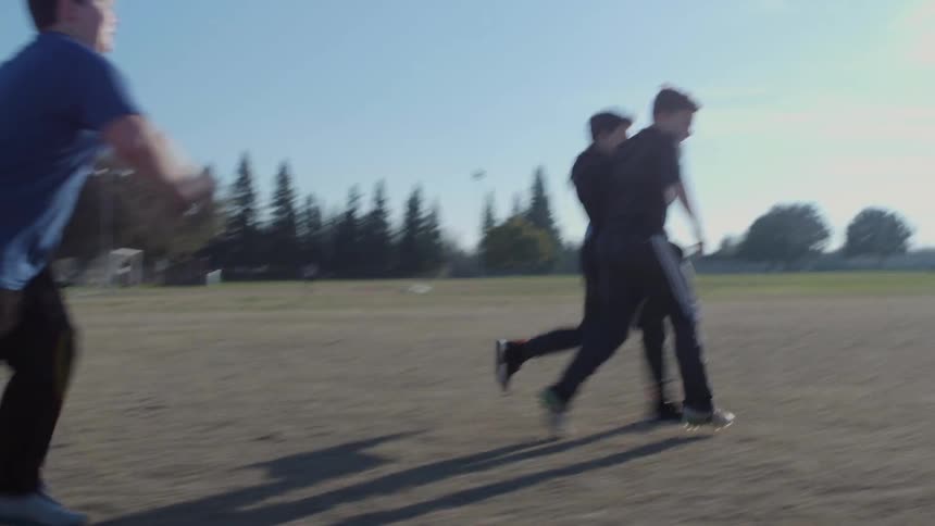 A group of boys is playing soccer outside on a sunny day