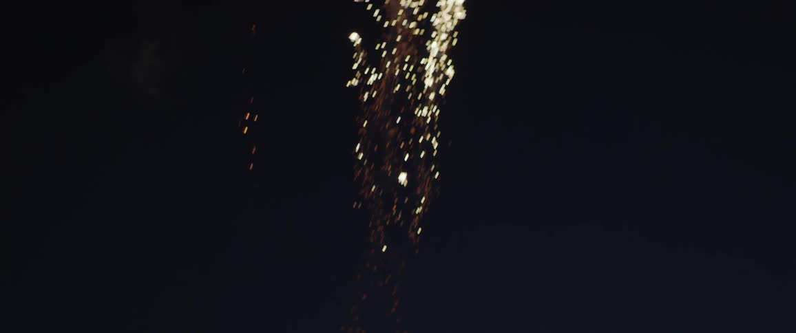 A young girl waves at the exploding fireworks