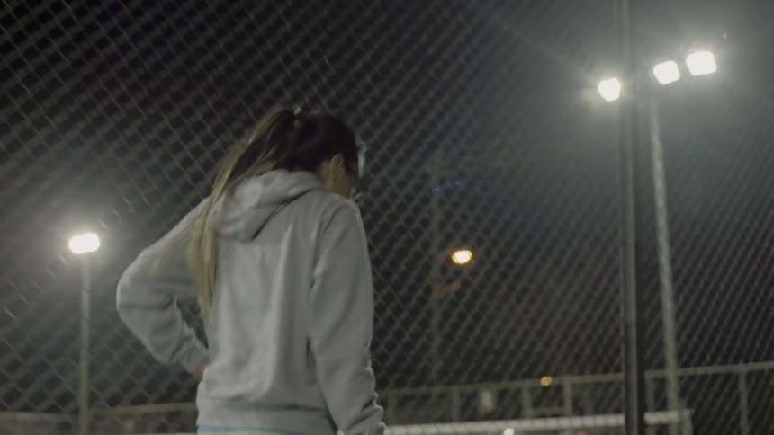 A girl takes a drink as she walks past a fence