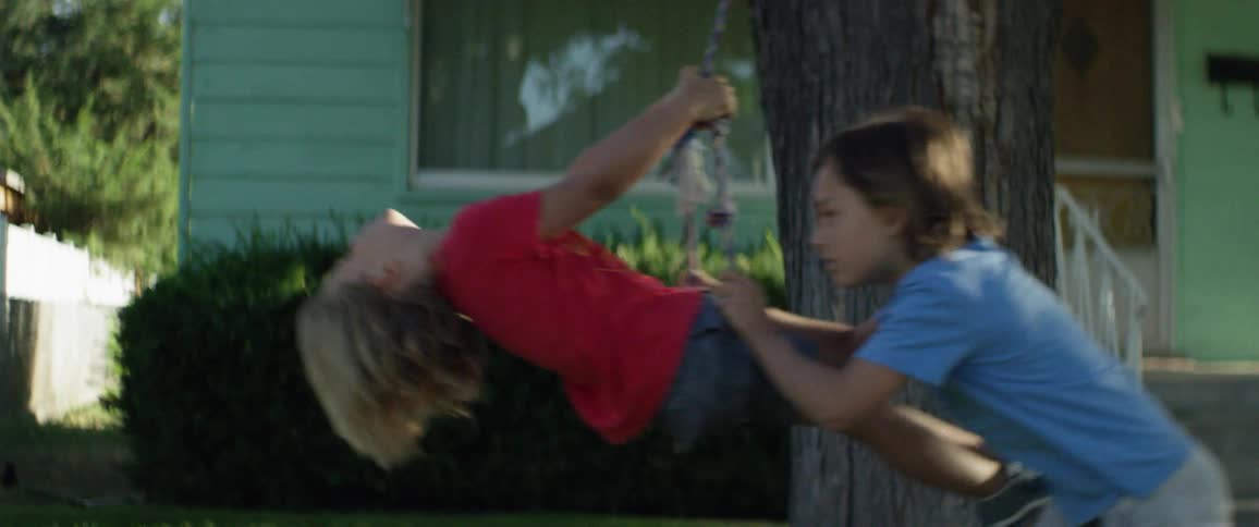 Two young boys play on a swing