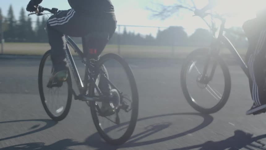 Boys ride bicycles in a parking lot