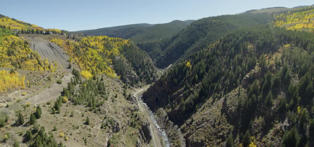 Stream flows through tree covered mountains on a sunny day