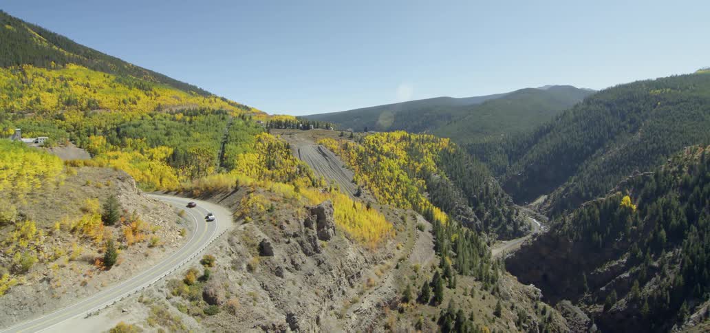 Vehicles drive down a winding road through the mountains