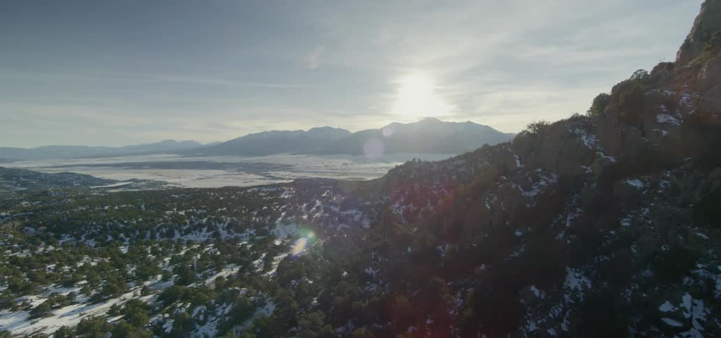 The sun shines on a valley between mountains