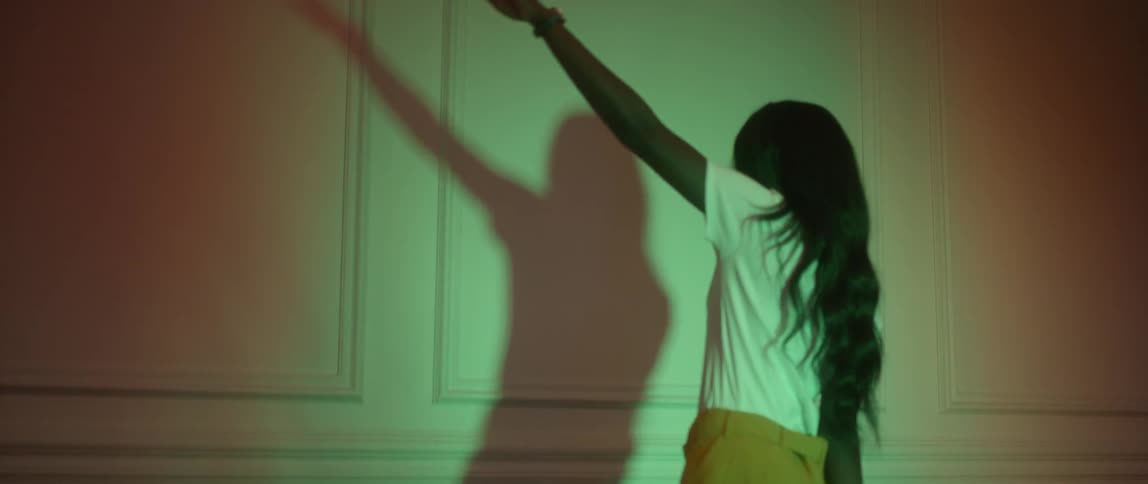 A woman dances and casts a shadow on the wall