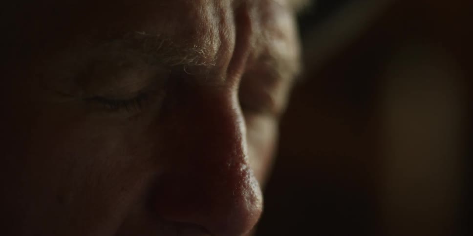 A man leans forward with his eyes closed