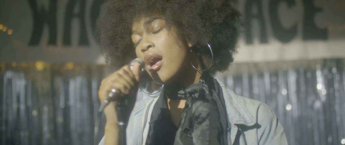 A black woman sings on stage