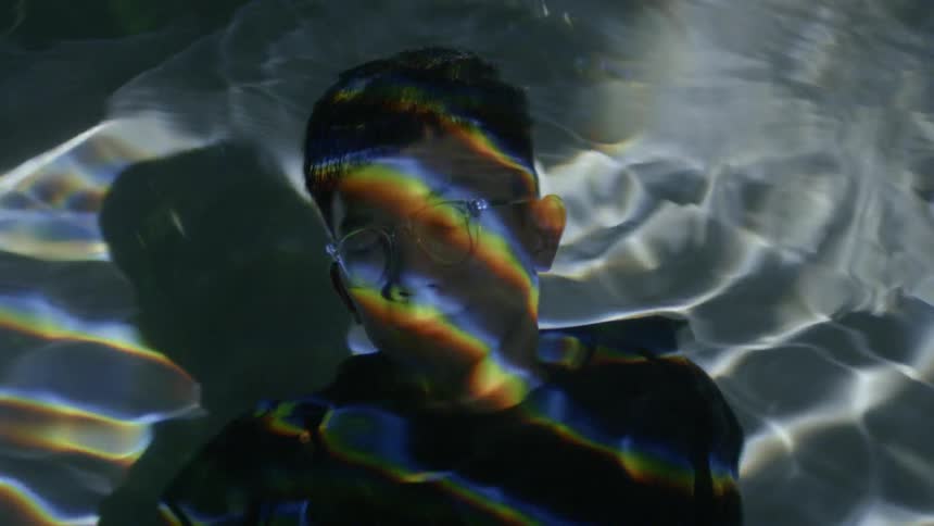 A young boy sits under the water