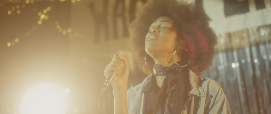 A woman shakes her head as she sings into a microphone