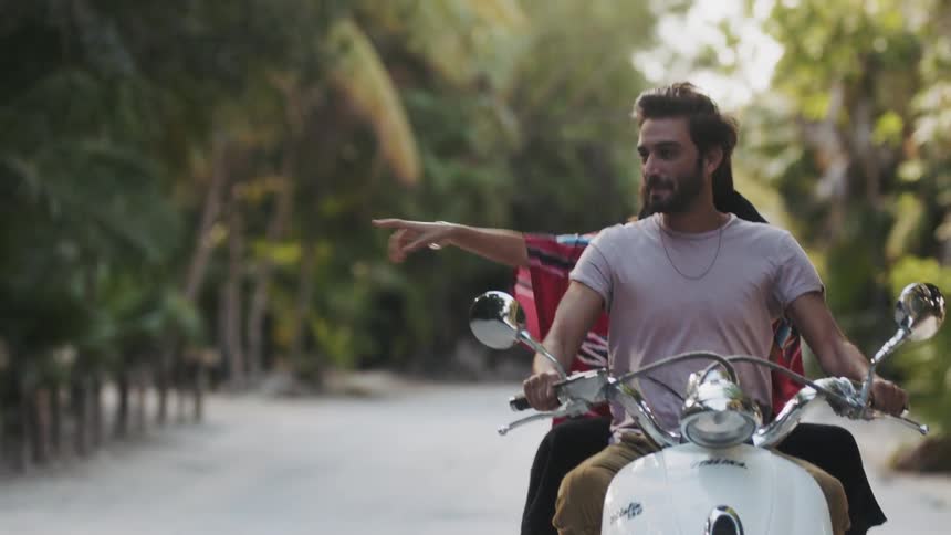 Man and woman ride motorcycle down a road