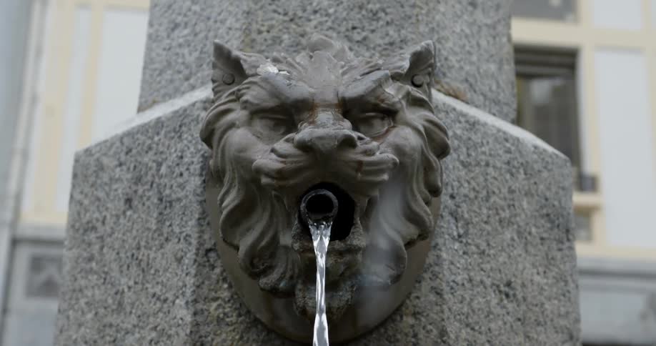 Water is pouring from the mouth of a figure in a water fountain during the day