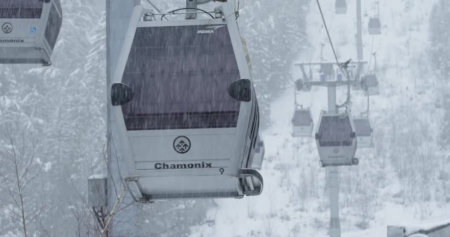 A gondola goes up a mountain on a snowy day