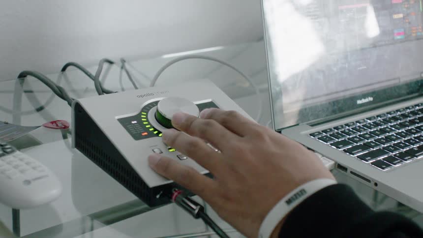 A person operates an audio mixing device near the laptop