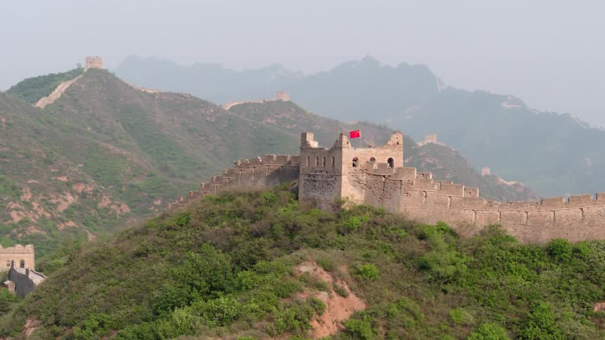 A red flag flies above a stone wall