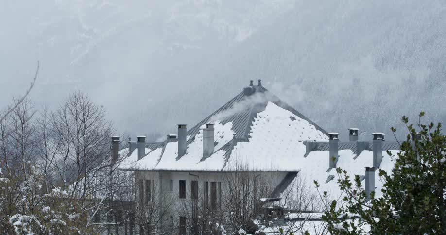 Smoke is pouring from a chimney in a building in an alpine village in winter