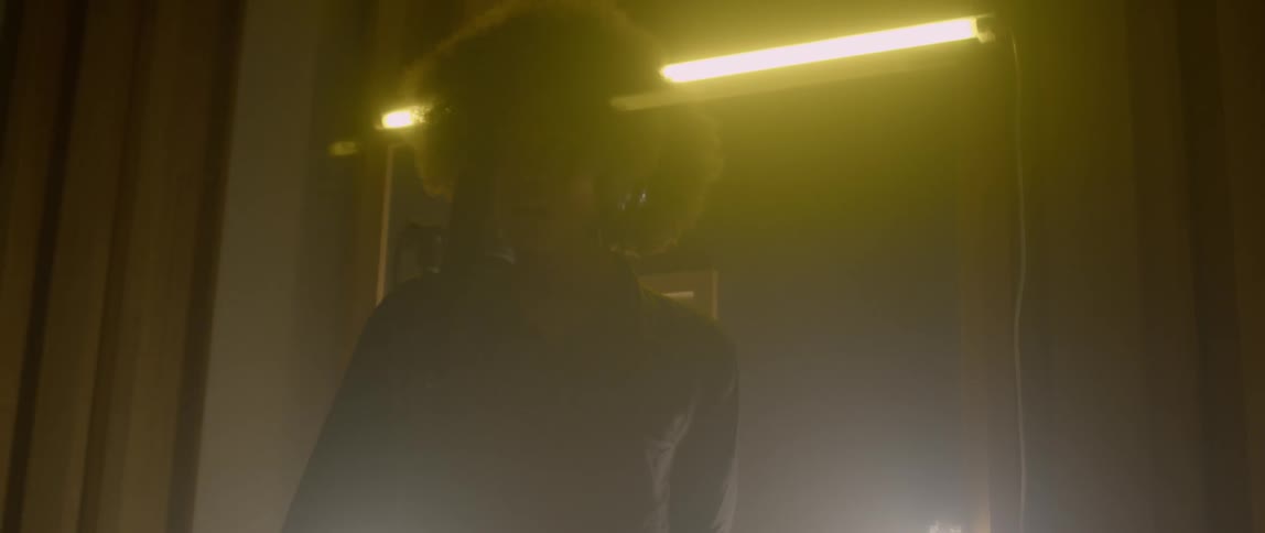 A woman sings into a microphone in a dark room