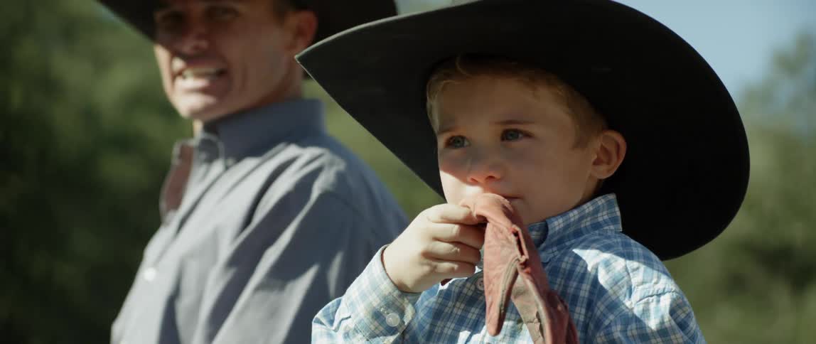 Young boy holds a glove as a man stands nearby