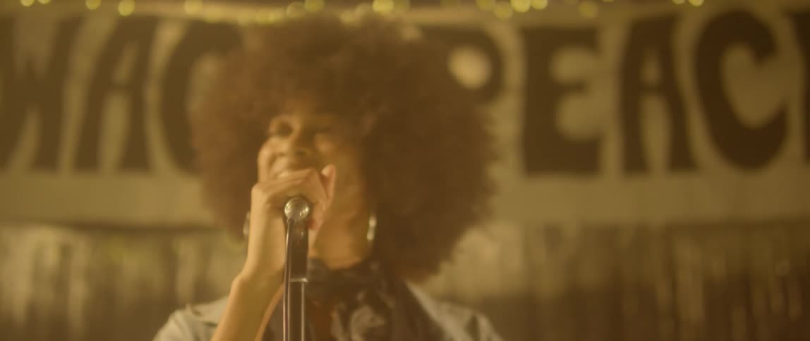 A woman sings into a microphone on stage