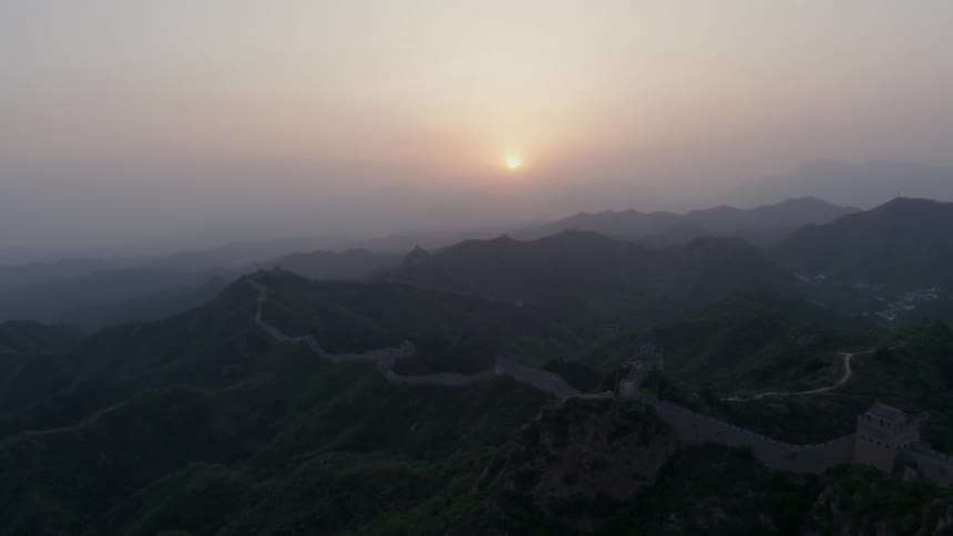 Sun setting behind some clouds and hazy mountains