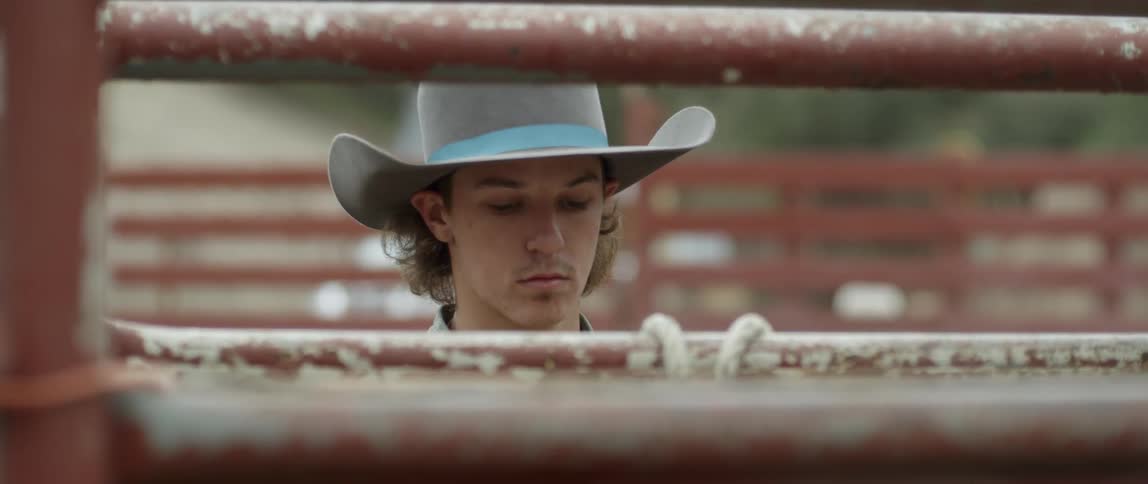 A cowboy ties a rope around a steel gate