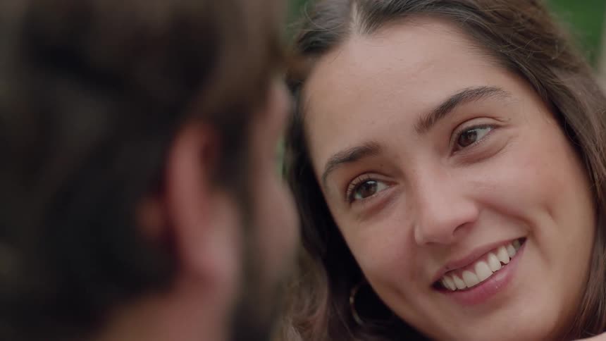 A woman touches a man's face while smiling