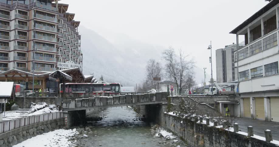 Buses cross a city bridge while it snows