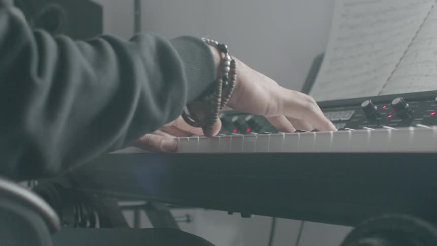 A person is playing the keyboard with sheet music in front