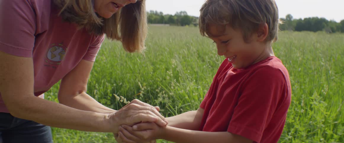 Woman places something inside a boy's hands