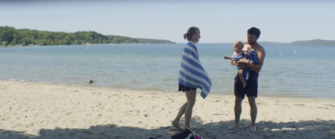 Two parents dry off with towels while holding a baby