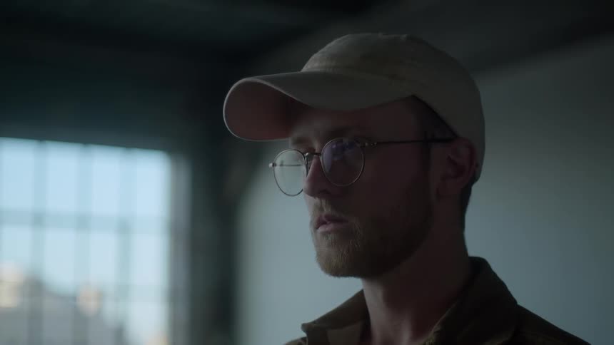Man in glasses blinks as he stares ahead