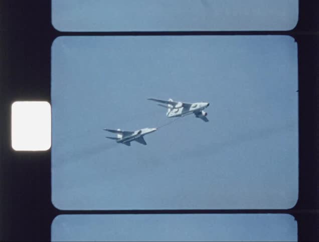A fighter jet is being refueled in mid-air on a sunny day