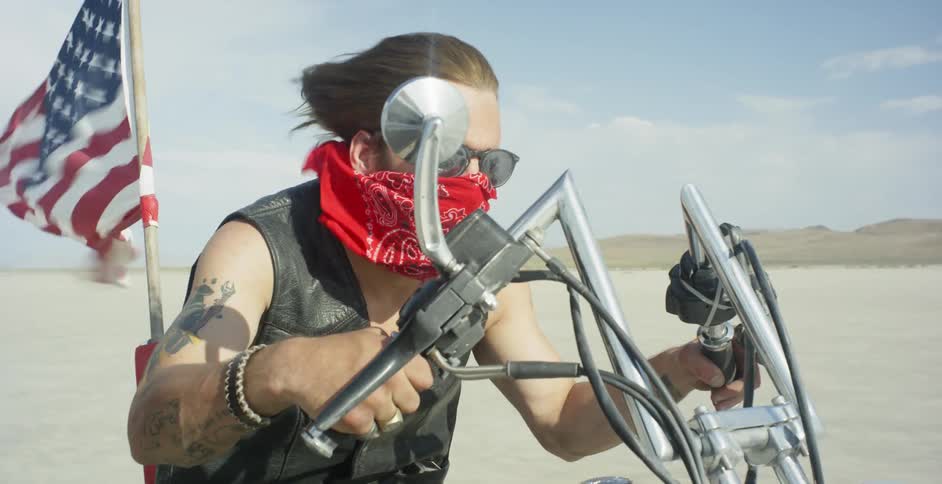 A man is riding a motorcycle in the desert on a sunny day