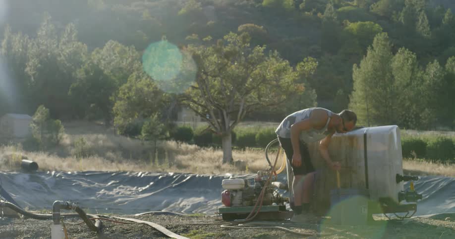 A man is working near a tarp and machine cleaning a bin