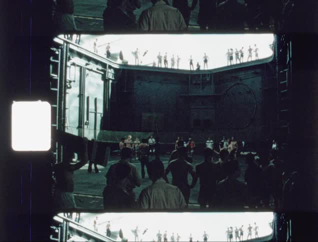 A group of people are gathered together near a metal wall