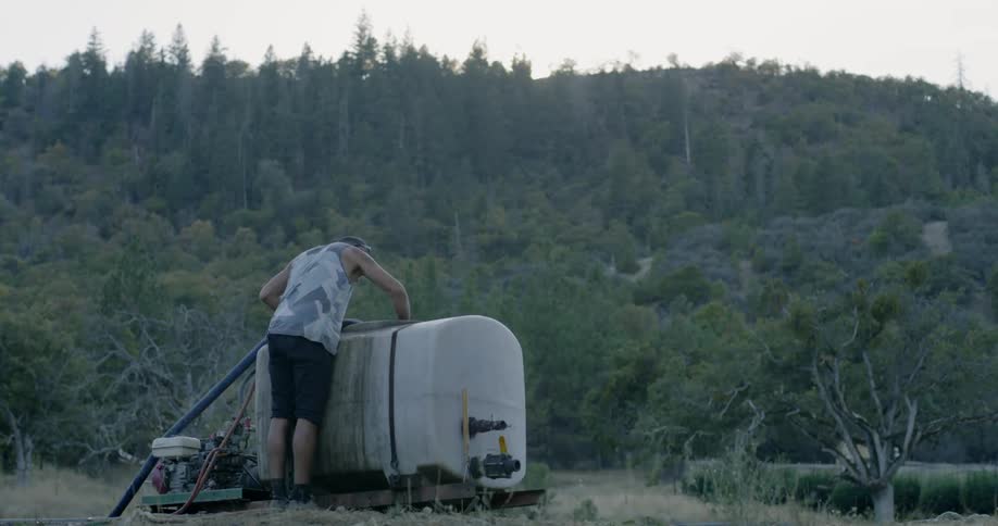 Man inserts a hose into a large white tank