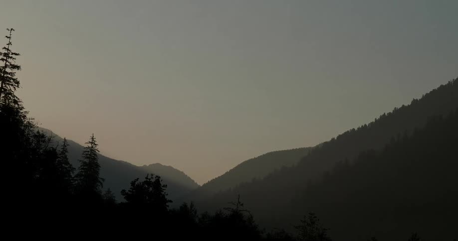 Sun sets over hills and trees